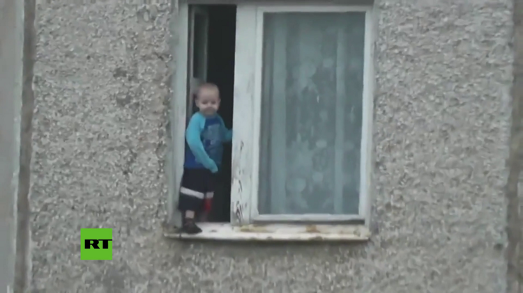 ¿Y los padres?: un niño ruso juega en la ventana de un piso octavo