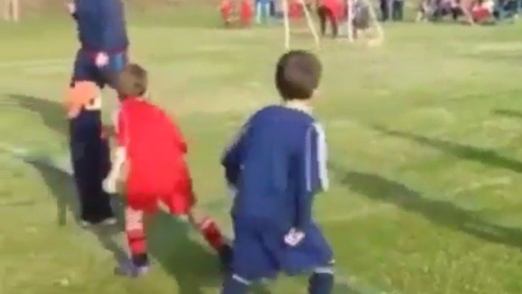 Un niño interrumpe su partido de fútbol para dar un abrazo a su hermanito