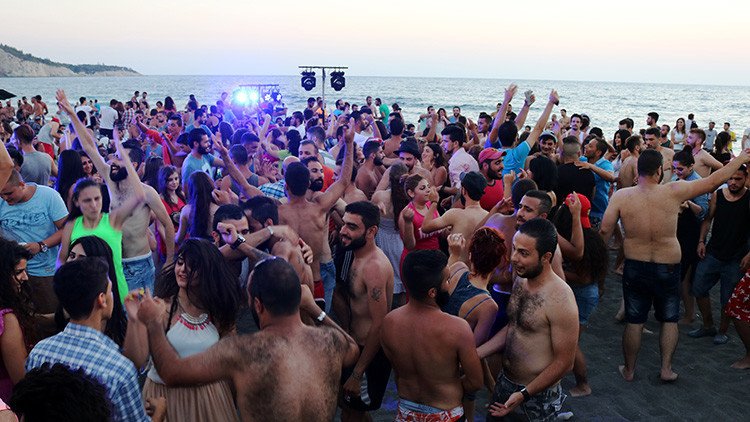 La otra cara de la guerra en Siria: Cientos de jóvenes se relajan, fuman y bailan en la playa 
