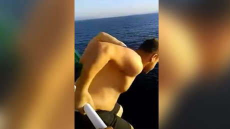 Un marinero salta de la cubierta de un petrolero para salvar a una ballena enredada