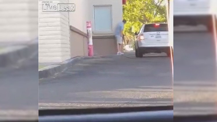 Un hombre hambriento roba un paquete de comida rápida en la ventanilla para autos