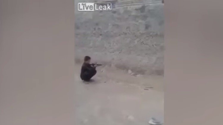 Un niño dispara con un rifle contra una lata sobre la cabeza de su amigo