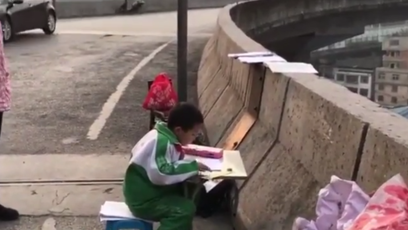 Un niño chino se ve obligado a hacer sus deberes en un paso elevado porque su casa es muy oscura