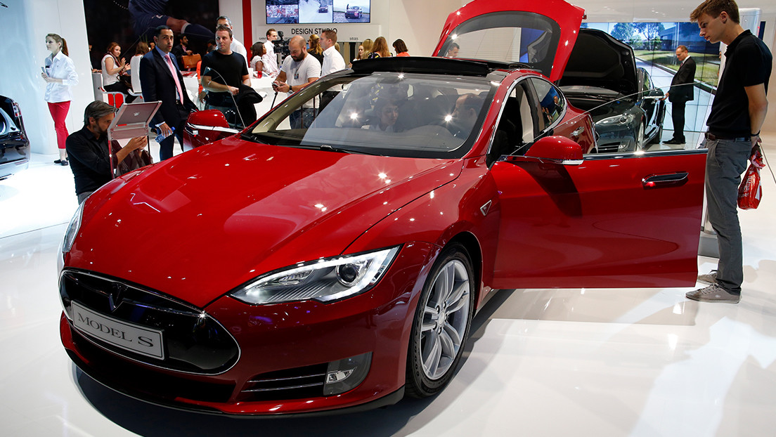 Visitors look at a Tesla Model S car displayed on media day at the Paris Mondial de l'Automobile