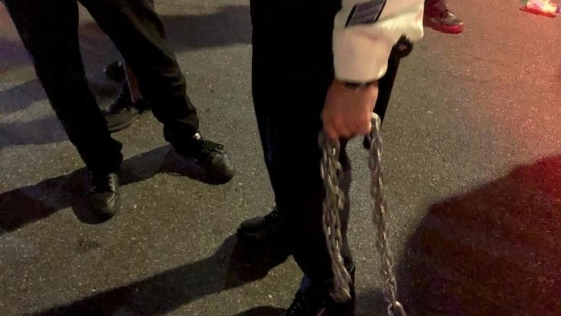 Un manifestante trata de estrangular a un agente con una cadena durante las protestas en Nueva York por el recuento completo de votos