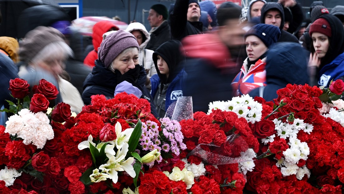 Enormes colas de gente llevando flores al edificio del Crocus City Hall