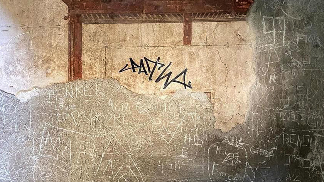 Turista firma con marcador permanente en la pared de una antigua ciudad romana
