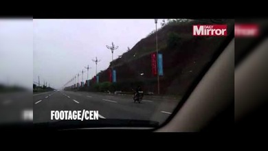 Maneja tranquilamente su moto de espaldas en mitad de la carretera