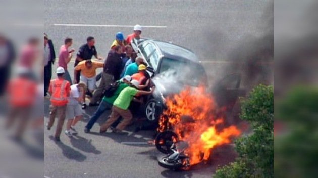 Transeúntes salvan a un motociclista atrapado bajo un coche en llamas