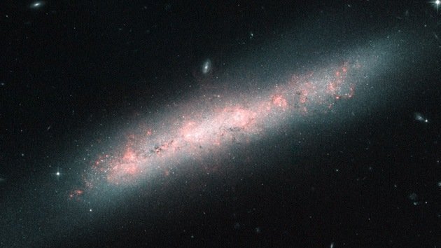 Captan la imagen de una galaxia encubierta por nubes rosas