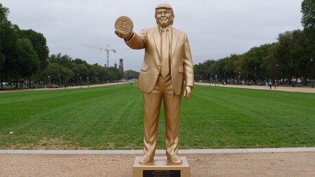 'Trump de ouro' segurando um Bitcoin aparece em frente ao Capitólio