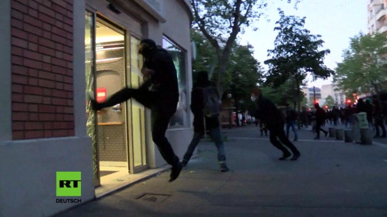 Vermummte Protestler schlagen Ladenfenster in Paris ein. 