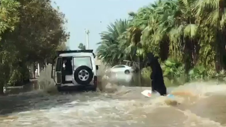 Frau im Nikab demonstriert ihr Surf-Talent in einer überfluteten Straße in Saudi-Arabien