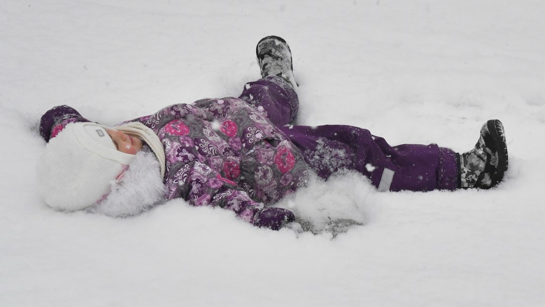 Strenger russischer Winter – Kinder schwingen auf Schaukel in Schneewehe