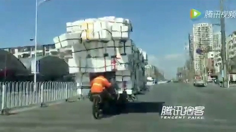 Chinese man defies gravity to transport mountain of boxes on tiny bike (VIDEO)