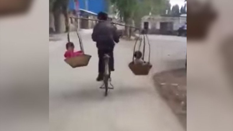 Dexterous dad carries children in baskets while balancing on bike (VIDEO)
