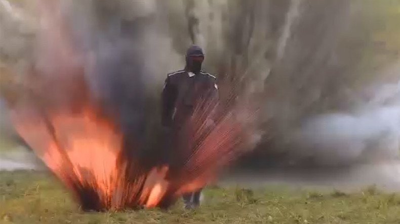 Russian woman casually walks through explosions & fire to test armor suit (VIDEO)