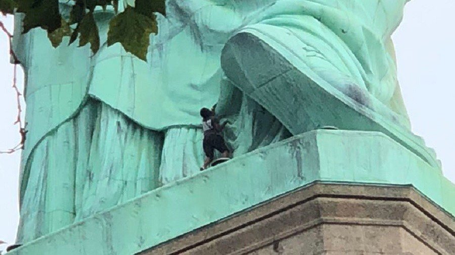Anti-ICE protester scales Statue of Liberty, prompting island evacuation & rescue (VIDEO)