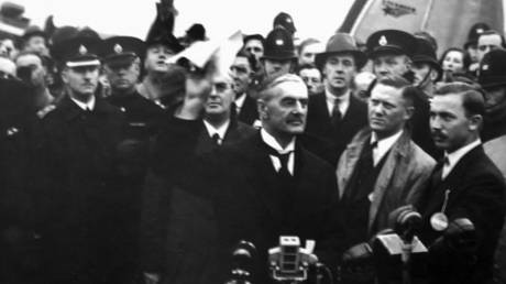 Prime Minister of the UK Arthur Neville Chamberlain waves the Munich Agreement (1938), which conceded the Sudetenland region of Czechoslovakia to Nazi Germany.