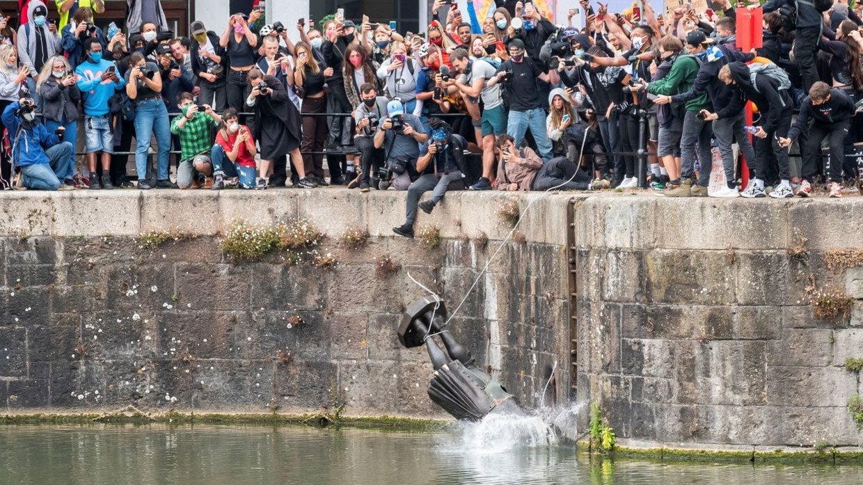 The statue of 17th century slave trader Edward Colston falls into the water in Bristol on June 7. © Keir Gravil via REUTERS