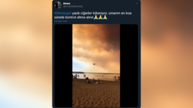 WATCH: Bathing tourists calmly look on as firefighting aircraft scoop water from the sea to tackle raging Turkish forest inferno