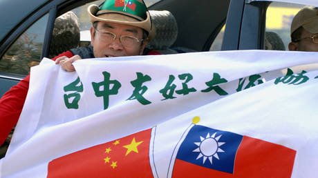 A pro-independence protester holds a banner printed with the national flags of Taiwan and China during a demonstration against the visit of China's chief Taiwan negotiator Chen Yunlin. © PATRICK LIN / AFP