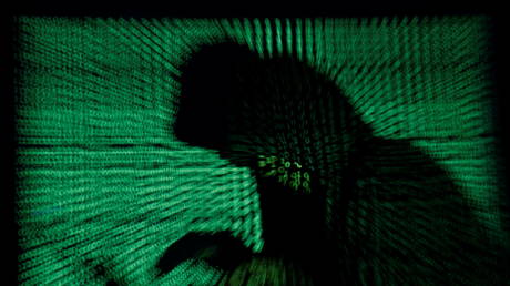 A hooded man holds a laptop computer as cyber code is projected on him. © Reuters / Kacper Pempel
