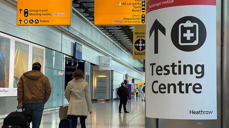Travellers pass a sign for a COVID-19 test centre at Heathrow Airport, London, Britain, February 13, 2021. © REUTERS / Toby Melville