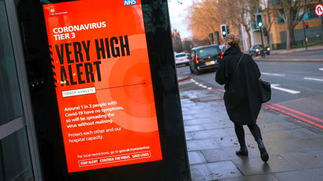 FILE PHOTO: A woman walks past a government sign alerting about the coronavirus disease in London, Britain, December 16, 2020 © Reuters / Hannah Mckay