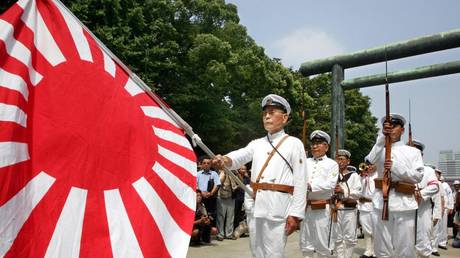 Holding an Imperial Navy flag, a Japanese veteran leads others to offer prayers for the country's war dead at Yasukuni Shrine in Tokyo, 15 August 2005. © AFP PHOTO / Kazuhiro NOGI