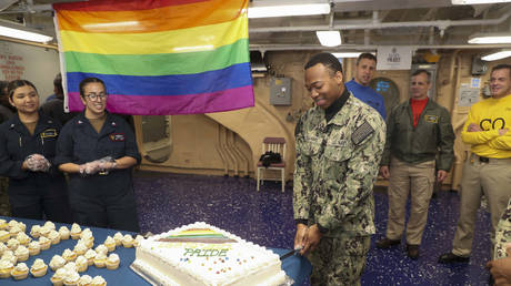  Intelligence Specialist Seaman Jalen Williams cuts a cake during a Pride Month celebration on the mess decks of the amphibious assault ship USS Tripoli (LHA 7). © US Navy / Christopher Sypert