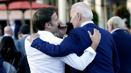 French President Emmanuel Macron whispers to U.S. President Joe Biden.