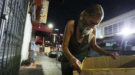 FILE PHOTO: A homeless man in the Skid Row area of Los Angeles is shown preparing a cardboard mat on which to sleep in September 2019.