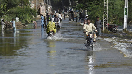 Residents make their way along a flooded street following heavy monsoon rains in Kandiaro area, some 100 km from Sukkur, Sindh province, on September 2, 2022.