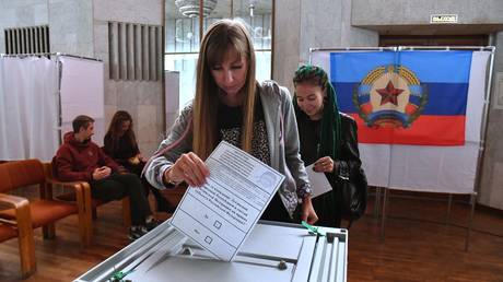 A girl votes in a referendum on the accession of the Luhansk People's Republic to Russia at a polling station.