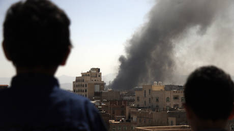 FILE PHOTO: Children look on as smoke billows above the residential area following airstrikes of the Saudi-led coalition targeting Houthi-held military positions in Sana'a, Yemen.