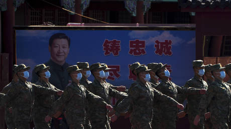 Chinese soldiers march past a poster of President Xi Jinping in Beijing, China, October 16, 2022. © AP Photo / Andy Wong.