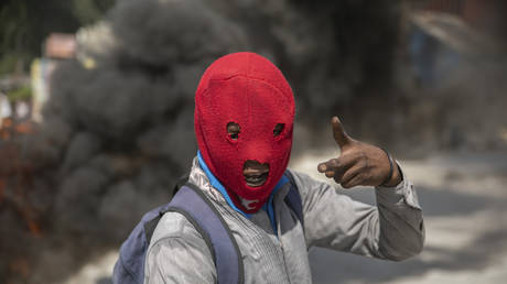 A protester gestures next to a burning tire during a demonstration against a requested foreign military deployment, in Port-au-Prince, Haiti, October 17, 2022.
