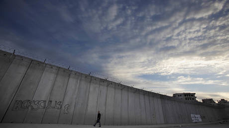 FILE PHOTO: A Palestinian man walks by a section of Israel's separation barrier in the occupied West Bank.