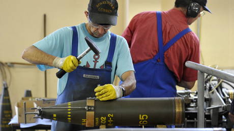 FILE PHOTO. Workers take apart an artillery shell at a weapons decommissioning facility in Germany.