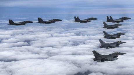 Four South Korean Air Force F-15Ks and four US Air Force F-16 fighters fly over South Korea during a precision bombing drill.