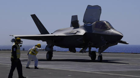 A crew member makes a signal to an F-35 aircraft for take off on the UK's aircraft carrier HMS Queen Elizabeth in the Mediterranean Sea on June 20, 2021.