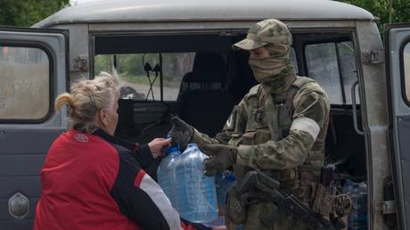 FILE PHOTO: Russian serviceman gives water to a woman in Mykolaiv region.