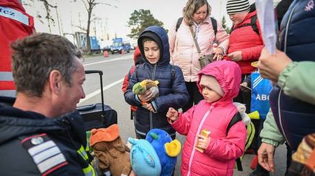 Ukrainian refugee children receive soft toys from a Romanian fireman after arriving at the Siret border crossing between Romania and Ukraine.