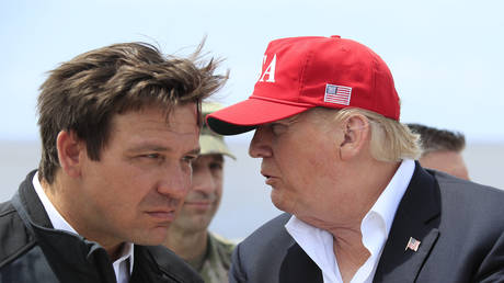FILE PHOTO: Then-US President Donald Trump talks to Florida Governor Ron DeSantis during a visit to Canal Point, Florida, March 29, 2019.