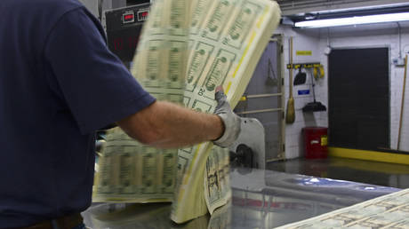 FILE PHOTO depicting an employee handling a pack of freshly printed sheets of 20 USD notes at the US Treasury’s Bureau of Engraving and Printing