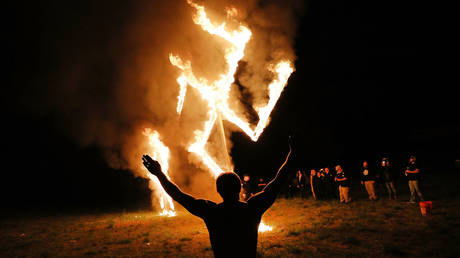 FILE PHOTO. Members of the National Socialist Movement, one of the largest neo-Nazi groups in the US, hold a swastika burning after a rally on April 21, 2018 in Draketown, Georgia, USA.