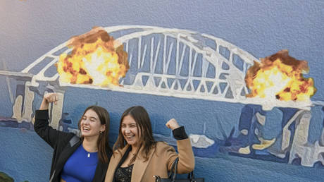 FILE PHOTO. Ukrainians celebrate in front of the large poster in form of postage stamp depicting Russia's Crimea Bridge on fire in Kiev, Ukraine.