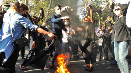 Iranian protesters set their scarves on fire while marching down a street on October 1, 2022 in Tehran, Iran.