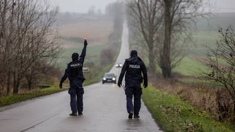 Police officers stop cars at the entrance to eastern Poland village of Przewodow where a missile strike killed two men.